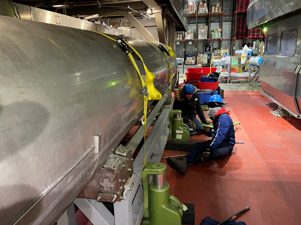 workers use hydraulic toe jacks to lift a hiperbaric chamber