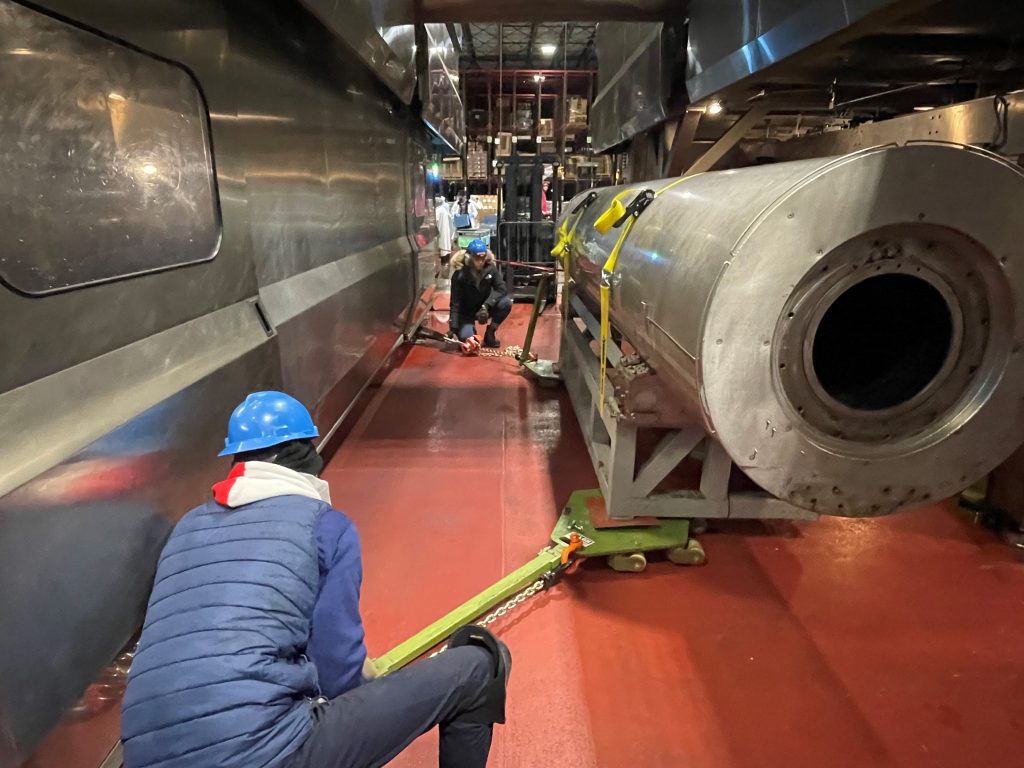 workers slide machine skates under a hiperbaric chamber to mobilize it 